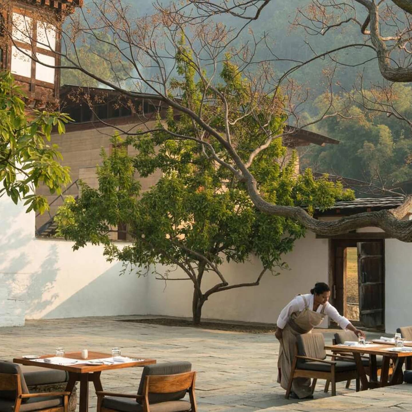 A courtyard restaurant at a Bhutanese hotel, tables laid under the trees